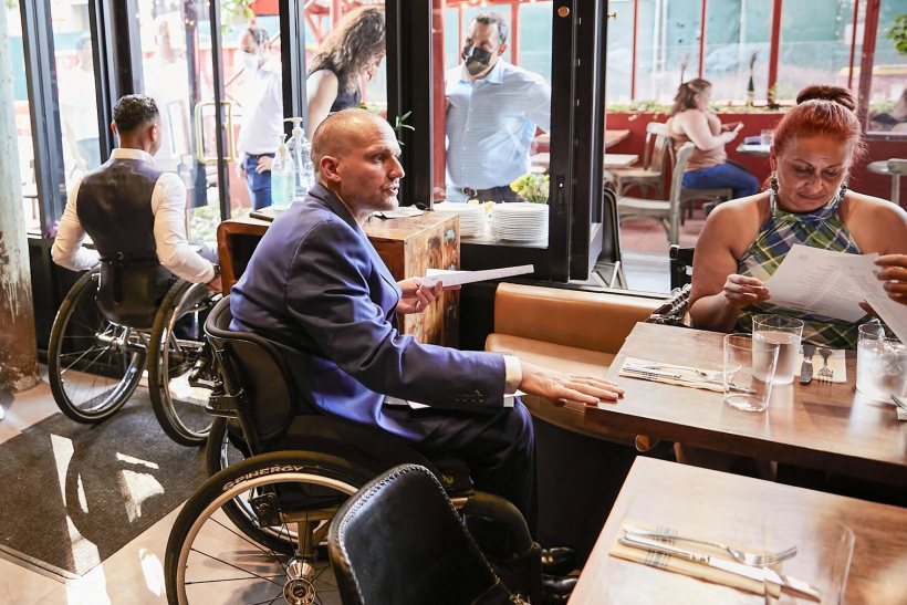 A man in a wheelchair serving people at a restaurant