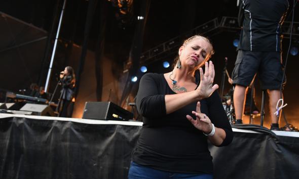 A sign language interpreter dressed in black signs for the audience at a live music concert