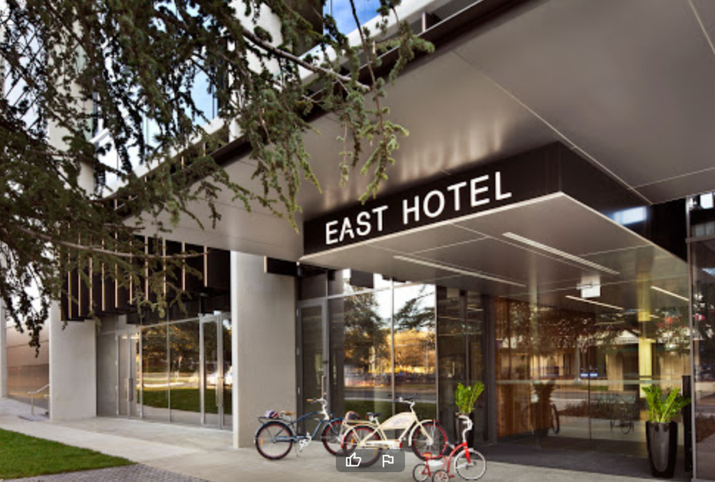 East Hotel entrance , 2 bicycles and a childs tricycle out front of the glass doored entrance