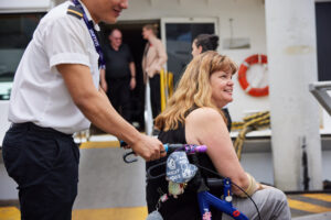 Crewmember escorting woman in wheelchair on deck 300x200
