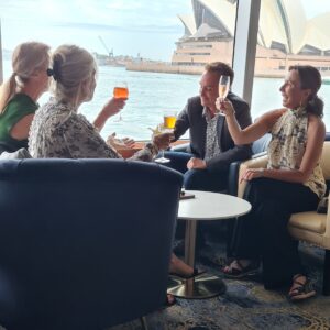 Four friends sitting together having drinks and looking at the harbour from inside the boat 300x300